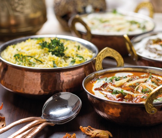 Metal bowls with various curries and rices in